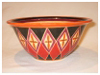 A Bali stoneware wide bowl, decorated with diamond shape geomatric design and glazed with red and black unerglazes on peach background - second view.